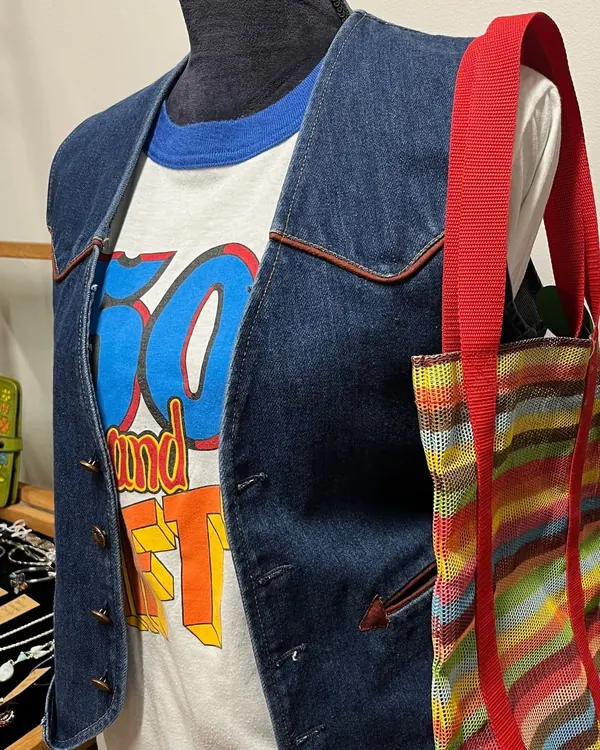 Denim vest over a graphic tee with a striped tote